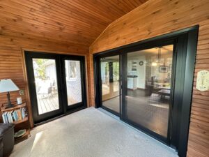 A sleek black patio door from EcoTech seamlessly blends indoor and outdoor spaces, enhancing the home's style and summer enjoyment.