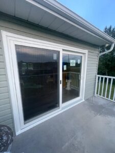 White sliding glass door leading to a patio or backyard, with natural light filtering through.