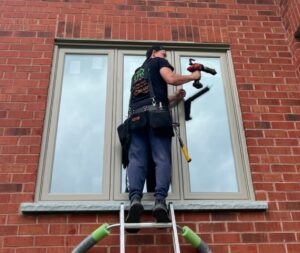 An installer carefully fitting a new window into place, demonstrating precision and expertise during the installation process.