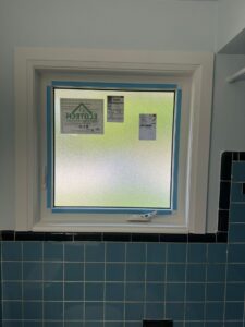 Frosted glass installed in a modern bathroom window, providing privacy while allowing natural light to filter through.