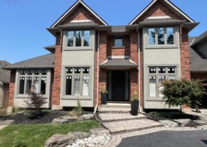 Exterior view of a modern home with energy-efficient thermal windows. The image highlights the sleek design and multiple panes of glass, showcasing features like triple glazing and Low-E coatings. The home is surrounded by greenery, emphasizing its enhanced comfort and energy efficiency.