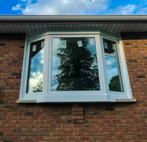 A close-up of a window framed with brickmold, highlighting the seamless integration between the window frame and the brick exterior of the home.