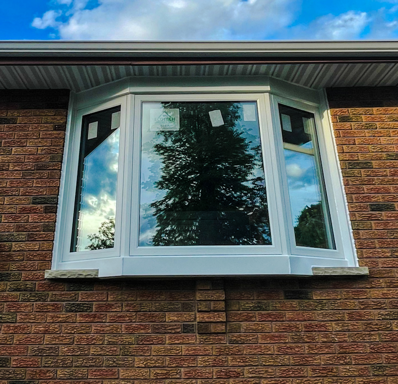 A close-up of a window framed with brickmold, highlighting the seamless integration between the window frame and the brick exterior of the home.