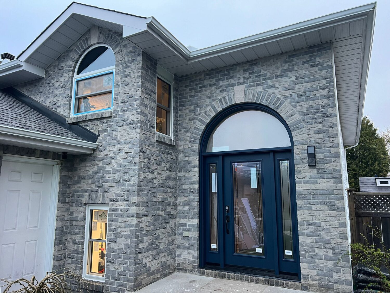 Home featuring a blue front door with sidelights and a curved transom window above, enhancing the entryway with stylish details and natural light.