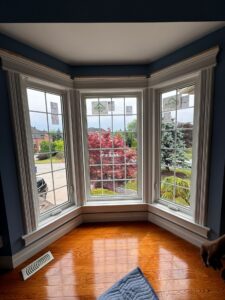 A bay window with three large glass panels extending outward from the exterior wall, offering a panoramic view and filling the room with natural light.